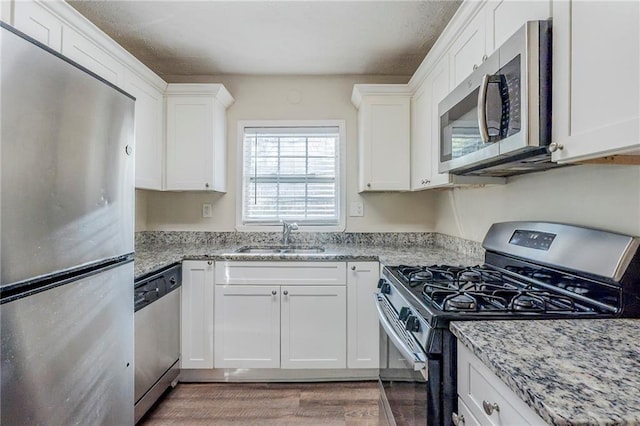 kitchen with white cabinetry, appliances with stainless steel finishes, a sink, and wood finished floors
