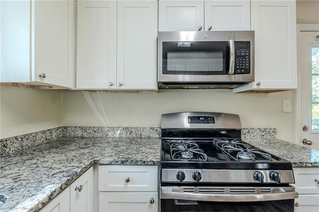 kitchen with white cabinets, light stone countertops, and stainless steel appliances