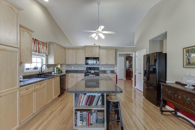 kitchen featuring dark countertops, black appliances, a kitchen island, and a sink