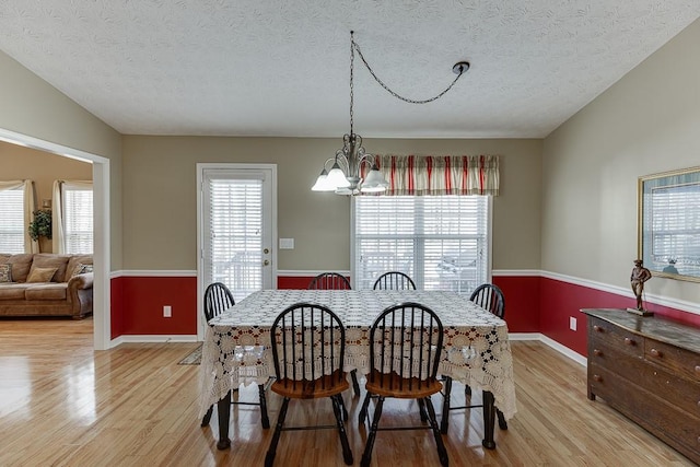 dining space featuring a healthy amount of sunlight, light wood finished floors, and an inviting chandelier