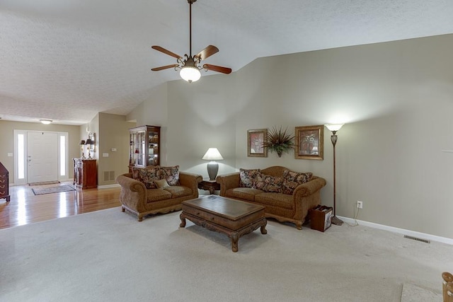 living area with high vaulted ceiling, baseboards, a textured ceiling, and light colored carpet