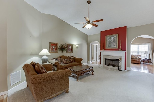 living area with light colored carpet, visible vents, a fireplace, and arched walkways