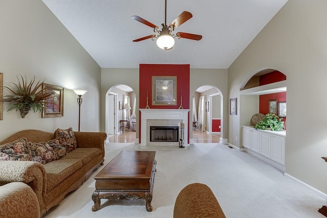 living area featuring high vaulted ceiling, a high end fireplace, light colored carpet, and baseboards