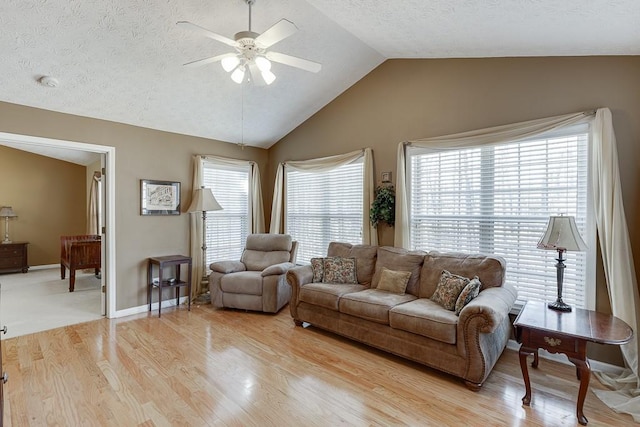 living area featuring ceiling fan, vaulted ceiling, a textured ceiling, wood finished floors, and baseboards