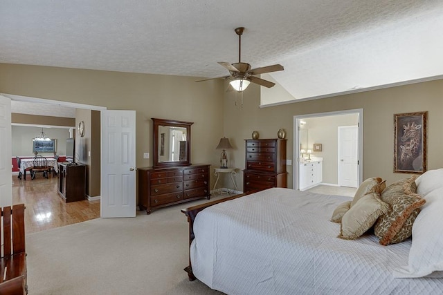 bedroom featuring lofted ceiling, a textured ceiling, connected bathroom, light carpet, and a ceiling fan