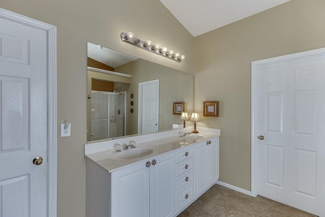 full bathroom featuring a stall shower, vaulted ceiling, a sink, and double vanity