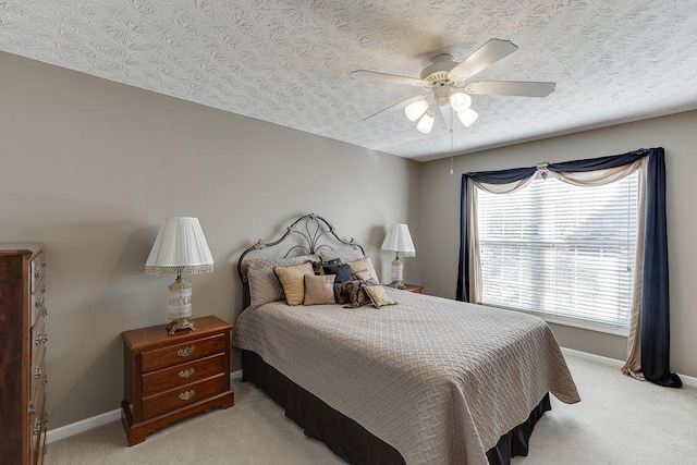 bedroom featuring ceiling fan, baseboards, a textured ceiling, and light colored carpet