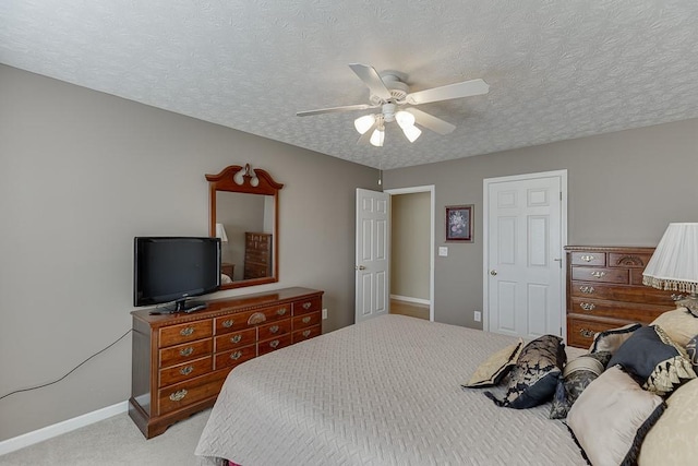 bedroom featuring light carpet, a ceiling fan, baseboards, and a textured ceiling