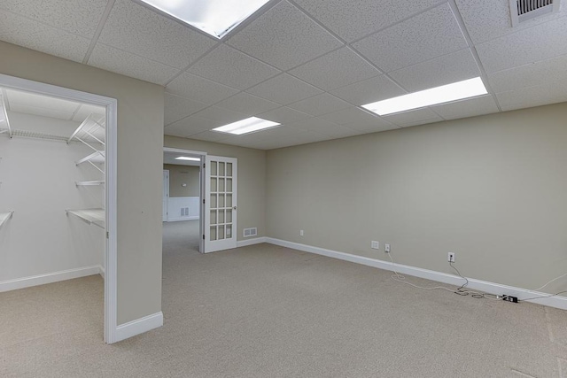 below grade area with baseboards, french doors, visible vents, and light colored carpet