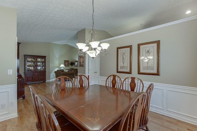 dining room with lofted ceiling, a textured ceiling, and light wood finished floors