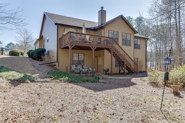 back of property with a deck, a chimney, and stairway