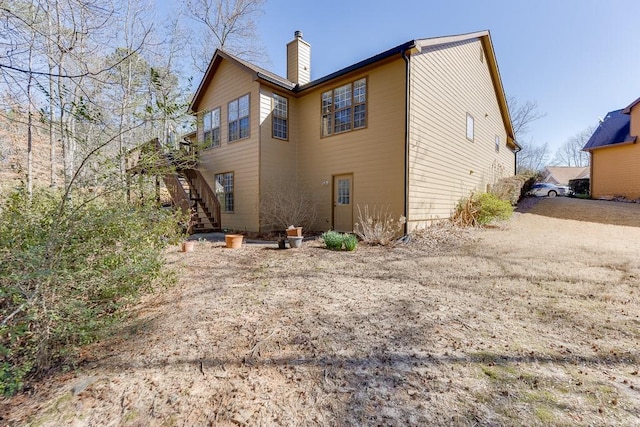 back of property with a chimney and stairway