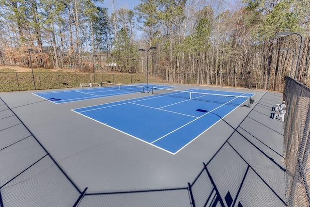 view of tennis court featuring community basketball court and fence