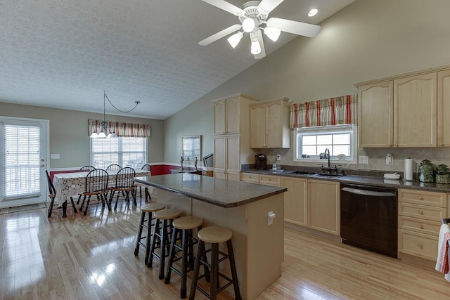 kitchen featuring a sink, dark countertops, dishwasher, and a center island