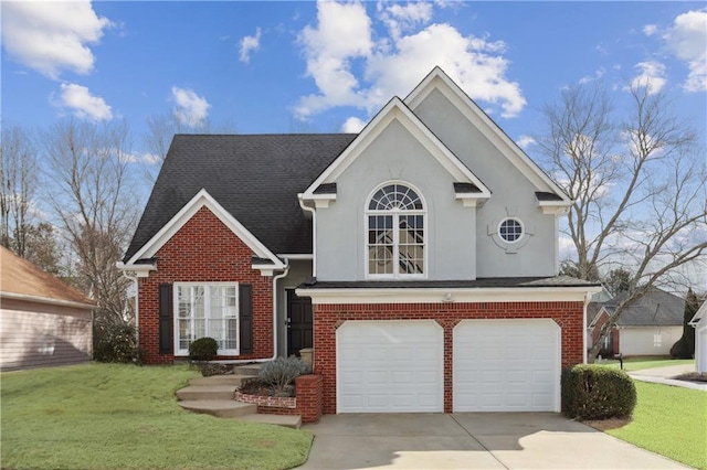 traditional home featuring a front lawn, driveway, an attached garage, brick siding, and stucco siding