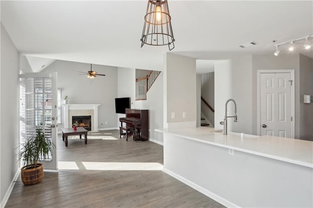 interior space featuring a sink, ceiling fan, wood finished floors, a lit fireplace, and baseboards