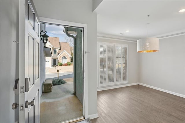 doorway featuring baseboards, wood finished floors, crown molding, and recessed lighting