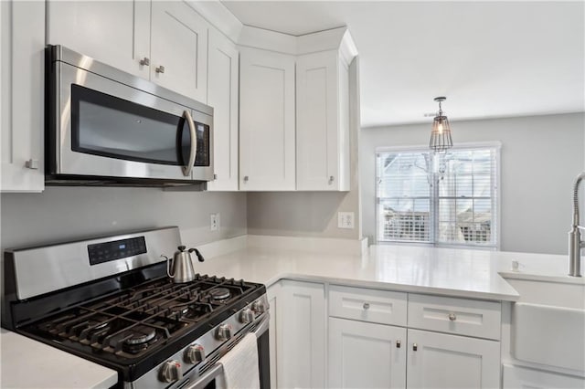 kitchen with stainless steel appliances, a sink, white cabinets, and light countertops