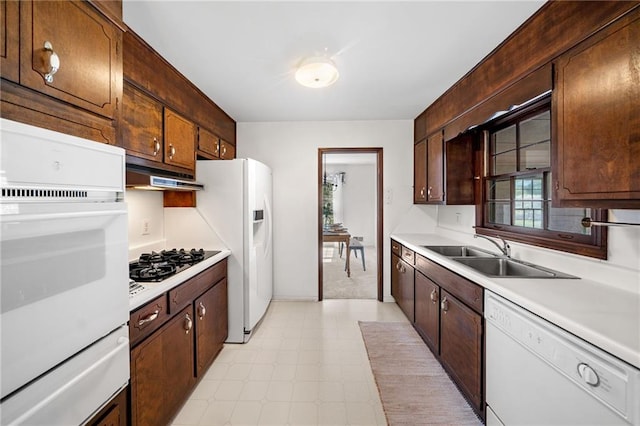 kitchen with white appliances, light countertops, a warming drawer, under cabinet range hood, and a sink