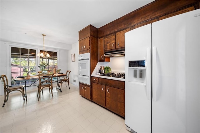 kitchen with an inviting chandelier, white appliances, a warming drawer, under cabinet range hood, and light countertops