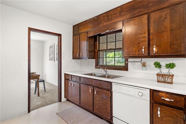 kitchen with light countertops, a sink, and white dishwasher