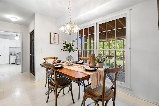 dining room with baseboards, light floors, and ceiling fan with notable chandelier