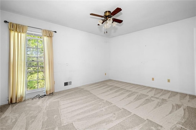 carpeted spare room with visible vents, baseboards, and ceiling fan