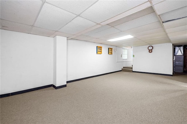 basement featuring carpet, a paneled ceiling, and baseboards
