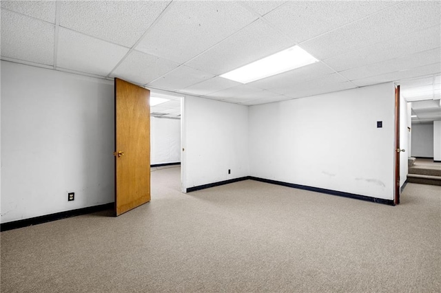 finished basement with baseboards, a drop ceiling, and stairs