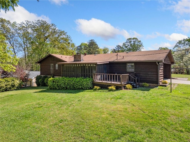 back of property featuring a garage, a wooden deck, a chimney, and a lawn