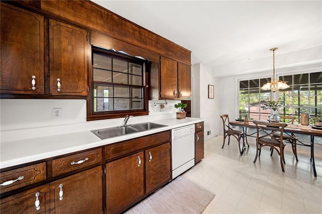 kitchen featuring a notable chandelier, light countertops, dishwasher, a sink, and hanging light fixtures