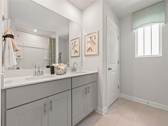 bathroom with baseboards, tile patterned floors, double vanity, and a sink