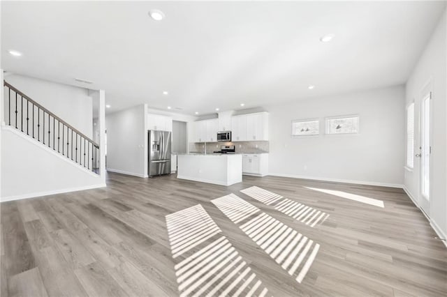unfurnished living room with plenty of natural light, light wood finished floors, recessed lighting, and baseboards