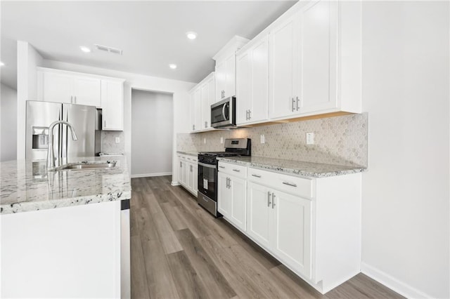 kitchen featuring visible vents, stainless steel appliances, light wood-style floors, and a sink