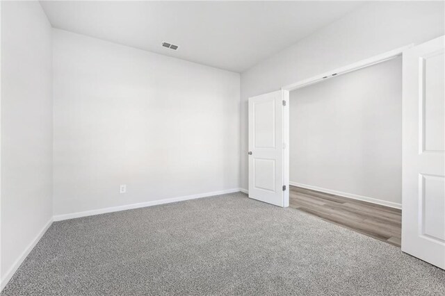 empty room featuring visible vents, carpet flooring, and baseboards