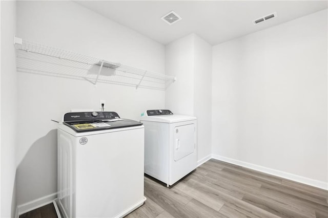 laundry room featuring visible vents, separate washer and dryer, light wood-style flooring, and laundry area