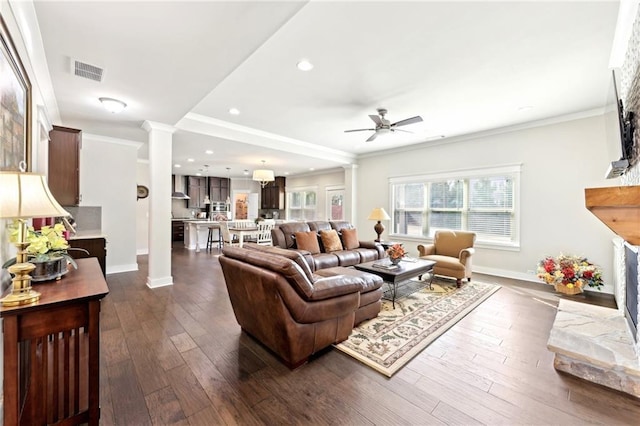 living area featuring visible vents, ornamental molding, a ceiling fan, and decorative columns