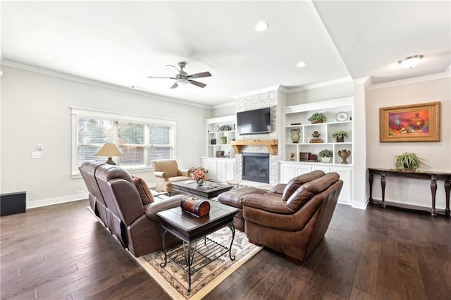 living area featuring a large fireplace, ornamental molding, dark wood-style floors, and ceiling fan