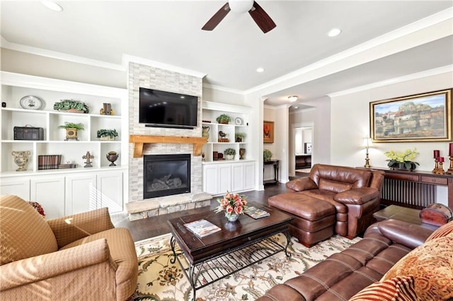 living room featuring a stone fireplace, crown molding, a ceiling fan, and wood finished floors