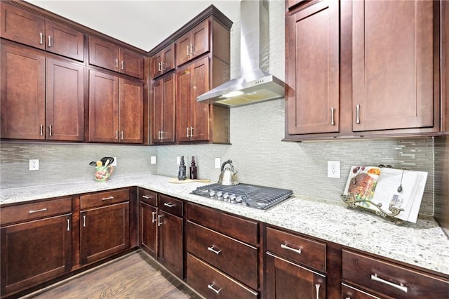 kitchen with light stone countertops, tasteful backsplash, wall chimney exhaust hood, and stainless steel gas cooktop