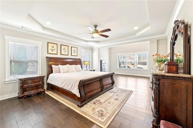 bedroom with a tray ceiling, baseboards, visible vents, and dark wood-style flooring