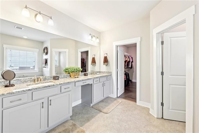 bathroom featuring double vanity, a spacious closet, visible vents, and a sink