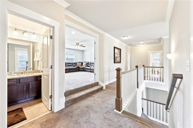 corridor with an upstairs landing, light colored carpet, crown molding, and baseboards