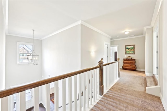 corridor with baseboards, carpet, ornamental molding, an upstairs landing, and an inviting chandelier