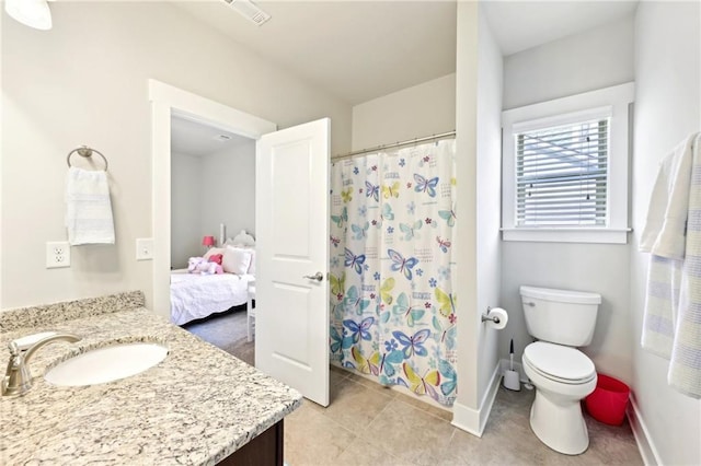 ensuite bathroom with vanity, toilet, baseboards, and tile patterned flooring