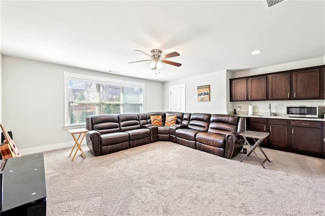 carpeted living area featuring recessed lighting, baseboards, ceiling fan, and a sink