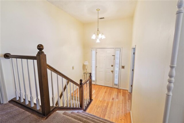 entrance foyer with a chandelier, a towering ceiling, and light hardwood / wood-style flooring