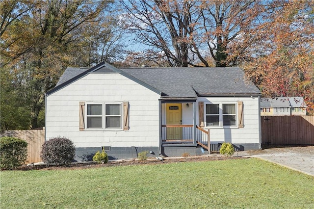 view of front of home featuring a front lawn, fence, and a shingled roof