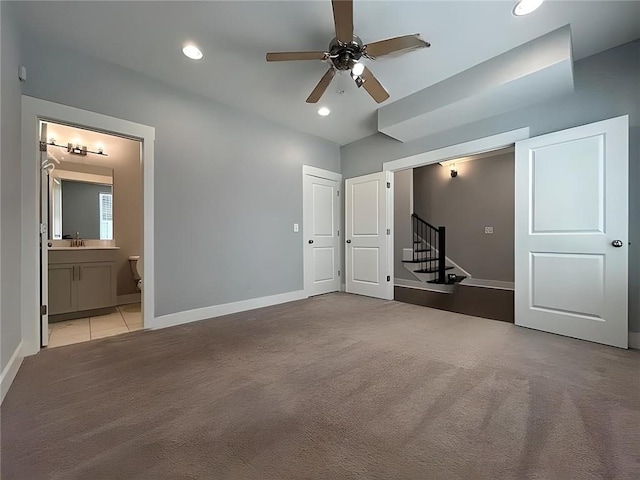 interior space featuring ceiling fan, light carpet, and connected bathroom