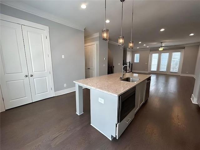 kitchen featuring a center island with sink, sink, ceiling fan, appliances with stainless steel finishes, and decorative light fixtures